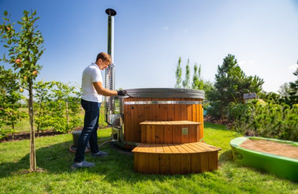 man near wood burning hot tub in the garden