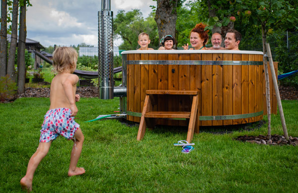 Boy runs towards wood burning hot tub with big family